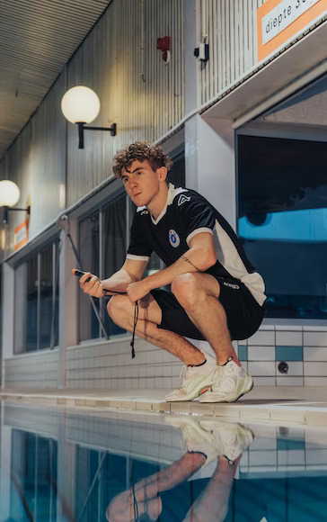 a male swim coach bending to stare at the swimming pool