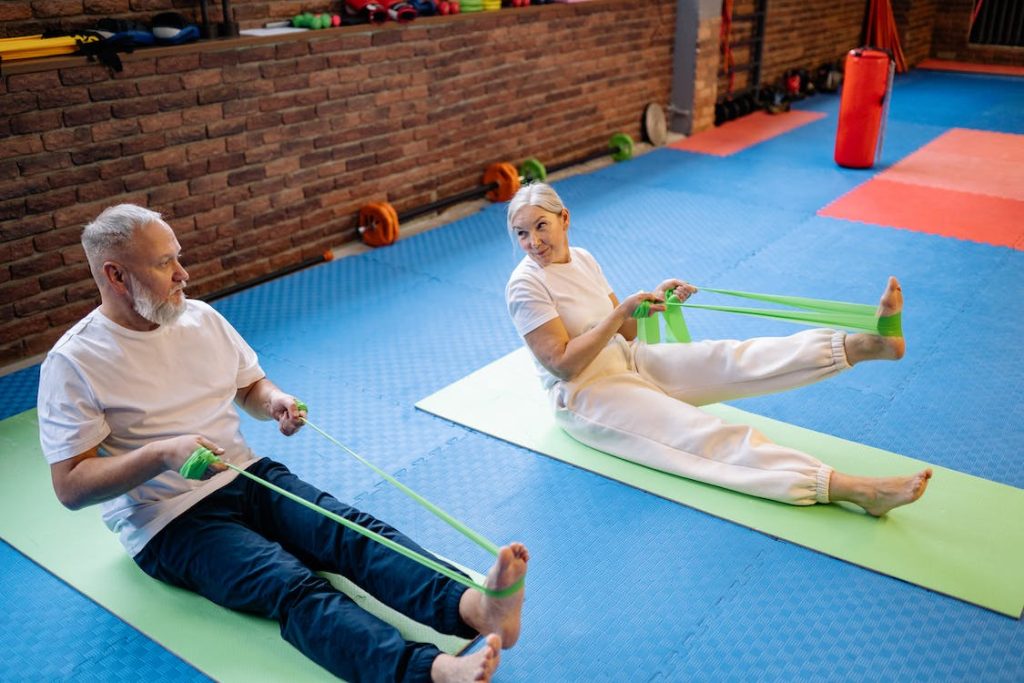 old woman and man doing the band swimmers workout using resistance band and mat