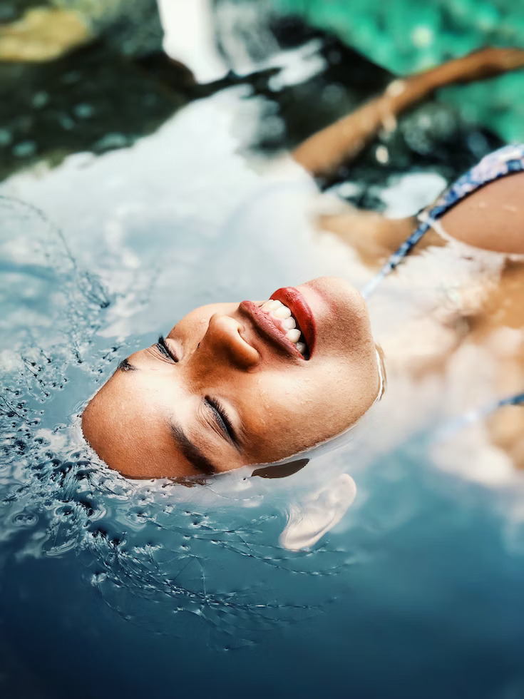 female swimmer relaxing in an outdoor black swimming pool