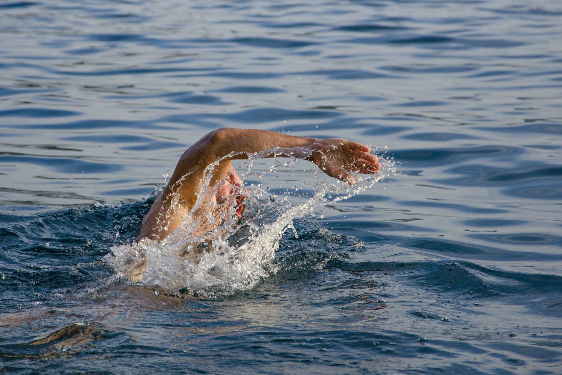 person swimming on body of water doing freestyle strokes