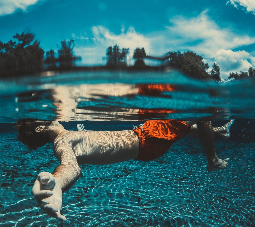 a short male swimmer swimming under the water