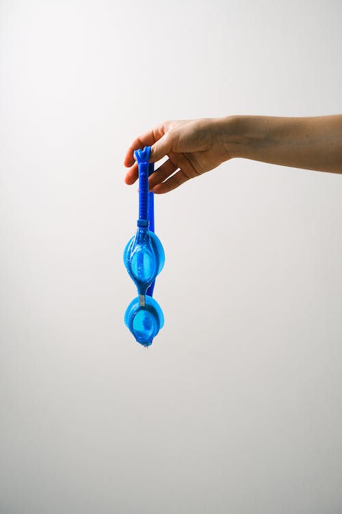 a hand holding a blue swim goggle