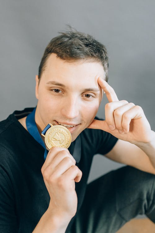 male swimmer biting his gold medal after a tie for gold