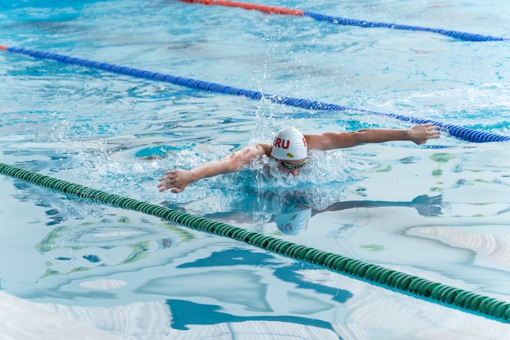 male swimmer swimming in the pool with a white swim cap