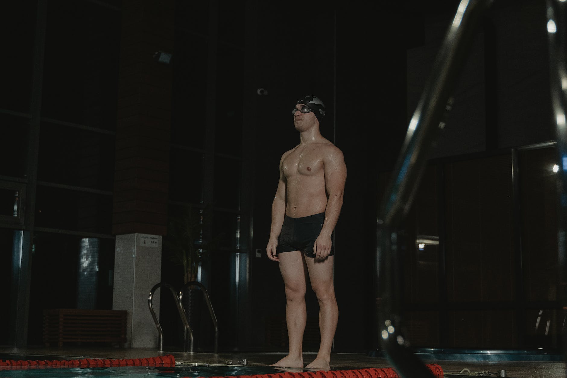 topless man in black shorts standing on poolside