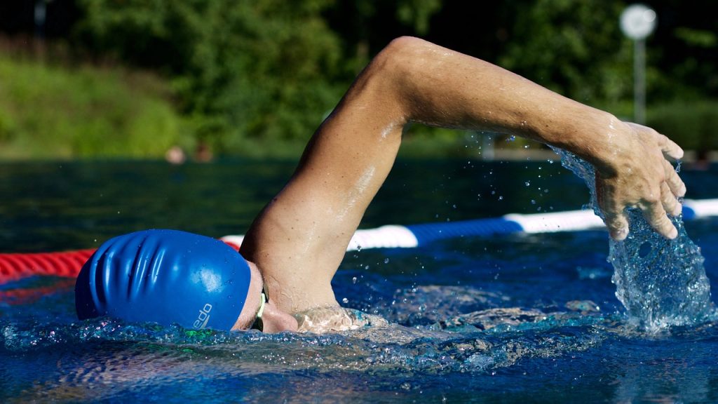 swimmer swimming in a pool with blue swim cap