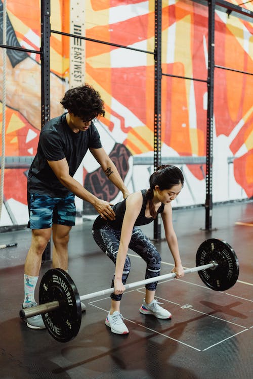 female swimmer lifting weight with a male coach