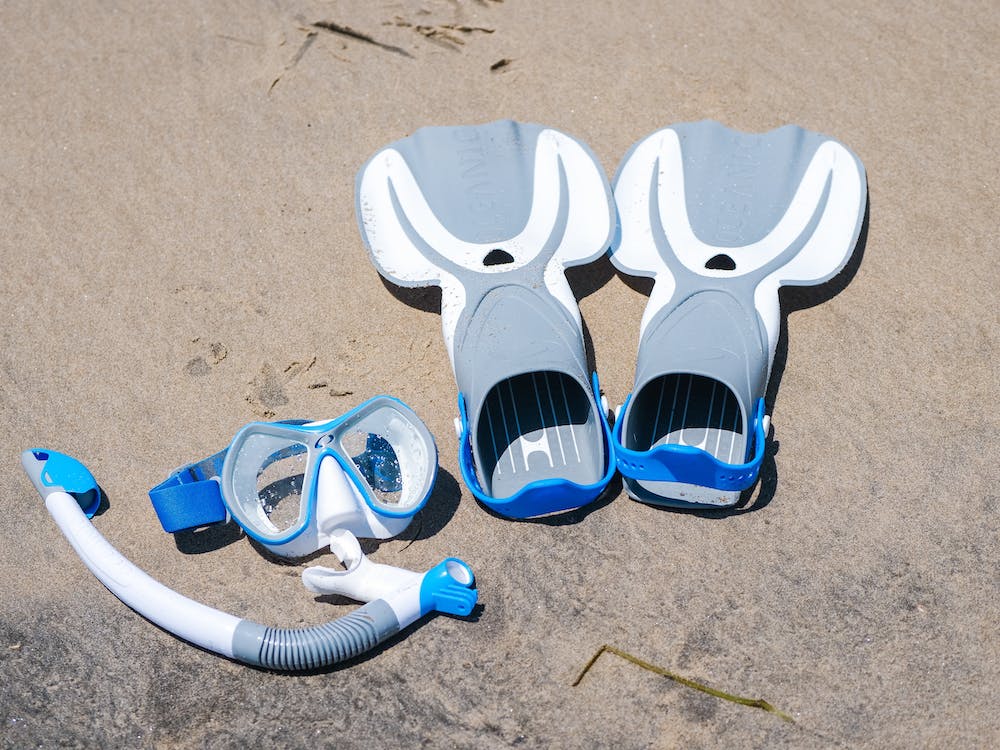 swim snorkel gears placed on the beach sand