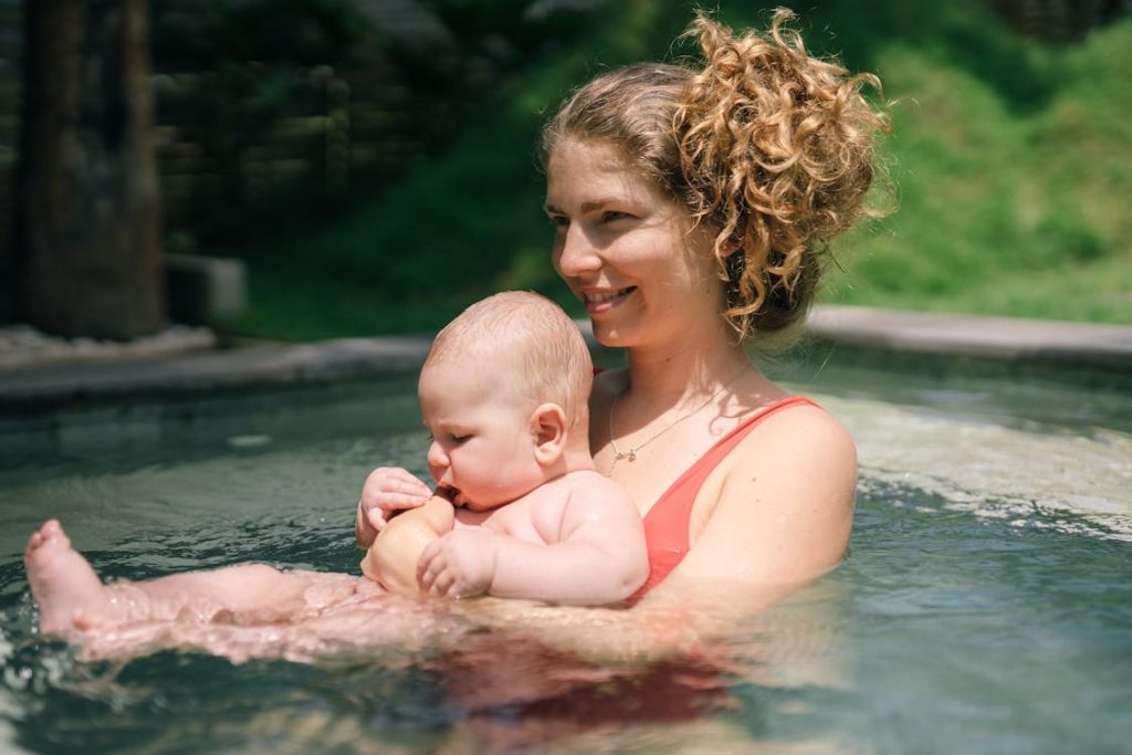 mother teaching her infant to swim in the pool