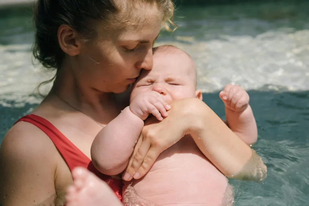 a mother holding her infant in a swimming pool