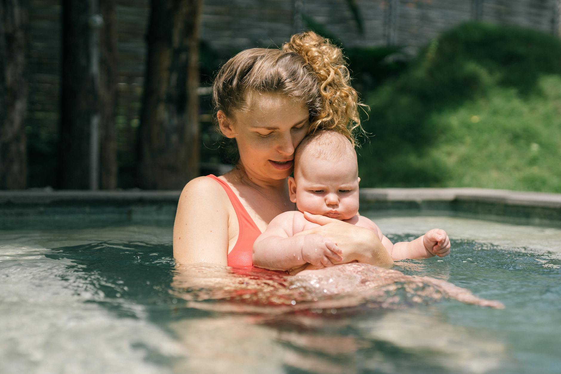 a mother carrying her baby while in a swimming pool